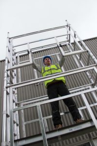 Image of a person safely using an access scaffold tower. They have been sufficiently trained with PASMA training. Access towers are safety equipment for working at height but are only safe when used safely by the person operating on them.